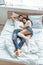 Handsome man in jeans and beautiful and smiling woman hugging in bedroom.