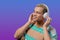 Handsome man listening music, enjoying dance with headphones on violet studio background. Radio, wireless modern sound