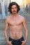 Handsome man with long hair and beard. He is posing in front of camera just with open jeans and showing his muscles. Abdominals