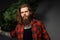 Handsome man with long hair holding a synthetic christmas tree