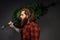 Handsome man with long hair holding a synthetic christmas tree