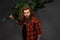 Handsome man with long hair holding a synthetic christmas tree