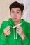 Handsome man with a lost face holding a menstruation cotton tampon, wearing a green hoodie in a blurred background