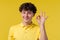 Handsome man makes hand sign okay, ok gesture. Happy guy, correct perfect choice, great deal, yellow background