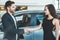 Handsome man manager and beautiful brunette woman client shaking hands after succesful deal in dealership center