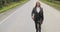 Handsome man in office suit with longboard walking down road in city outskirts.