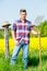 Handsome man with pitchfork standing in front of yellow field