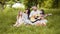 Handsome man playing guitar for his charming wife and two cute daughters. Happy caucasian family sitting on soft blanket