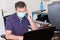 Handsome man in protective face mask is talking on phone working computer from home office during Coronavirus COVID-19 virus