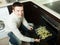 Handsome man putting fish into oven at kitchen