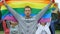 Handsome man with rainbow flag amid protesters for gay rights, LGBT pride event