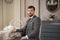 Handsome man seating on the chair at the table in retro interior