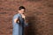 Handsome man in shirt singing with microphone near brick wall.