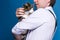 Handsome man in shirt and suspenders holding and stroking cute grey cat in golden crown