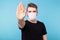 Handsome man showing gesture stop. Photo of healthy man wears protective mask against infectious diseases and flu