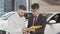 Handsome man signing papers at dealership after buying new automobile