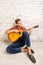 Handsome man siting on floor and playing on the guitar