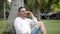 Handsome man sits under palm tree and calls on black smartphone