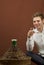 Handsome man smiling with a glass of white wine near a carboy