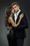 Handsome Man in Suit embracing Beautiful Girl side view over Gray. Fashion Couple. Couple in Love dating. Elegant Gentlemen and