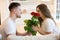 Handsome man surprising his beautiful wife with roses on saint valentine`s day, happy romantic unniversary