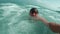 Handsome man swims azure tropical sea films himself on camera sea wave covers him with strength. Sea wave suddenly hits