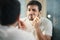 Handsome man trimming nose hair in bathroom