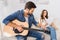 handsome man tuning guitar while his girlfriend