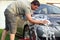 Handsome man washing car with a sponge and foam