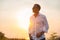 Handsome man in white shirt standing in sunset