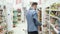 Handsome man in white shirt is talking on phone and buying groceries in supermarket