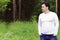 Handsome man in white stands in forest and looks away