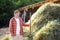 Handsome mature farmer turns the hay with a pitchfork on the backyard of farm. Growing livestock is a traditional direction of