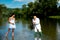 Handsome mature man fishing with young woman in white dress. Man with fishing rod and net. Happy bearded fisher in water