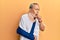 Handsome mature senior man wearing cervical collar and arm on sling feeling unwell and coughing as symptom for cold or bronchitis