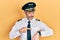 Handsome middle age man with grey hair wearing airplane pilot uniform in hurry pointing to watch time, impatience, upset and angry