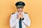 Handsome middle age man with grey hair wearing airplane pilot uniform laughing and embarrassed giggle covering mouth with hands,