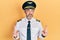 Handsome middle age man with grey hair wearing airplane pilot uniform pointing up looking sad and upset, indicating direction with