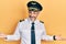 Handsome middle age man with grey hair wearing airplane pilot uniform smiling showing both hands open palms, presenting and