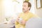 Handsome middle age man sitting on the sofa relaxed drinking a cup of coffe and smiling at the camera at home