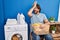 Handsome middle age man waiting for laundry surprised with hand on head for mistake, remember error