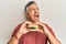 Handsome middle age mature man eating a tasty classic burger angry and mad screaming frustrated and furious, shouting with anger