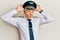 Handsome middle age mature man wearing airplane pilot uniform doing bunny ears gesture with hands palms looking cynical and
