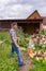 Handsome middle-aged man chopping wood with axe at backyard of country house. Man with chopper standing near woodpile