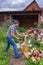 Handsome middle-aged man chopping wood with axe at backyard of country house. Man with chopper standing near woodpile