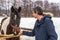 Handsome middle-aged man patting horse at ranch in snowy day. Winter weekend at farm, trip to countryside. Healthy lifestyle,