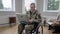 Handsome middle aged soldier waving and talking at laptop sitting on wheelchair at home. Portrait of disabled Caucasian