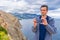 Handsome middle aged tourist man standing against beautiful seascape in cloudy day. Man using smartphone on background of sea,