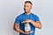 Handsome muscle man holding jar with savings smiling looking to the side and staring away thinking