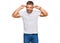 Handsome muscle man wearing casual white tshirt smiling pulling ears with fingers, funny gesture